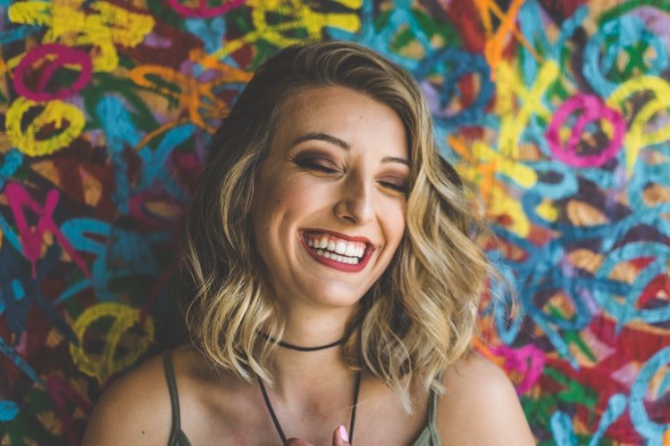 Mulher sorrindo em frente a um fundo colorido
