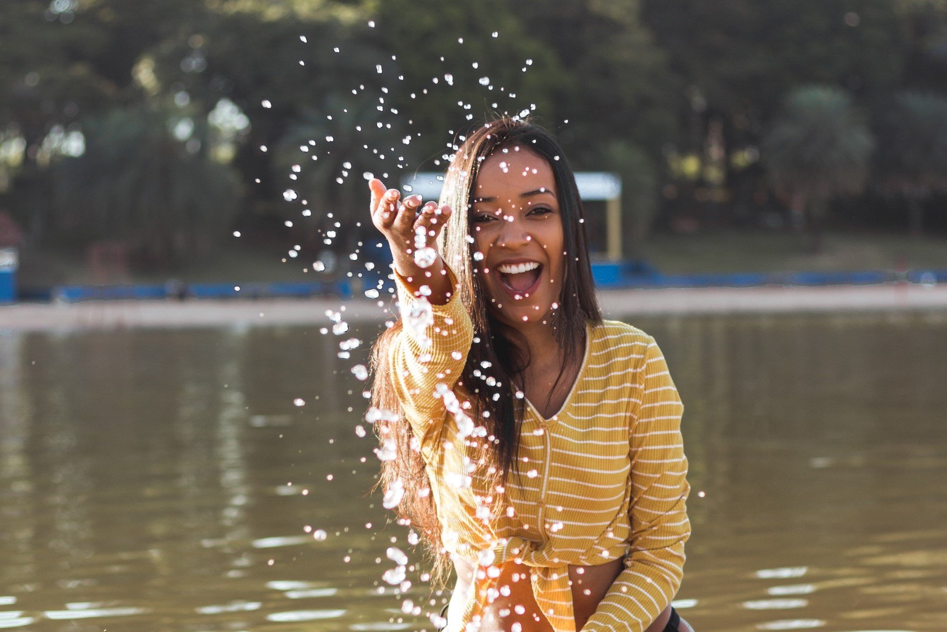Mulher sorrindo, jogando água na direção da câmera