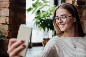 Mulher de óculos tirando selfie e sorrindo