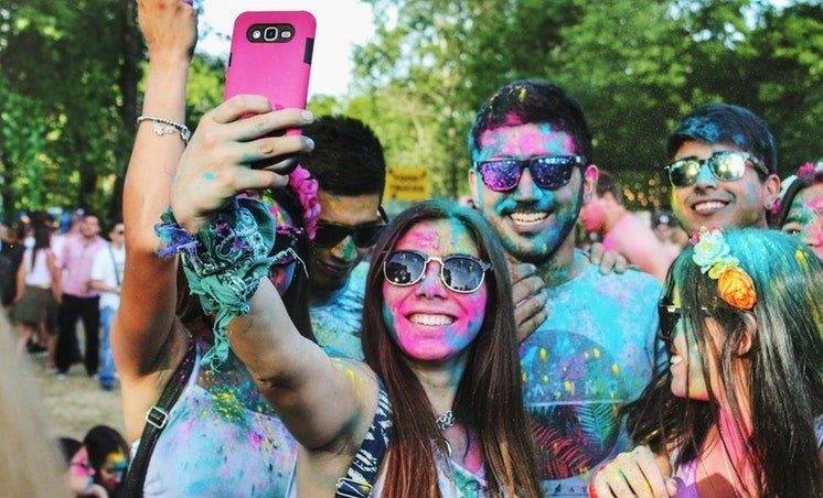 Amigos cobertos de pó colorido sorrindo para uma selfie