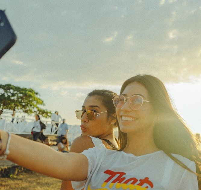 Duas amigas de óculos de sol tirando selfie e sorrindo
