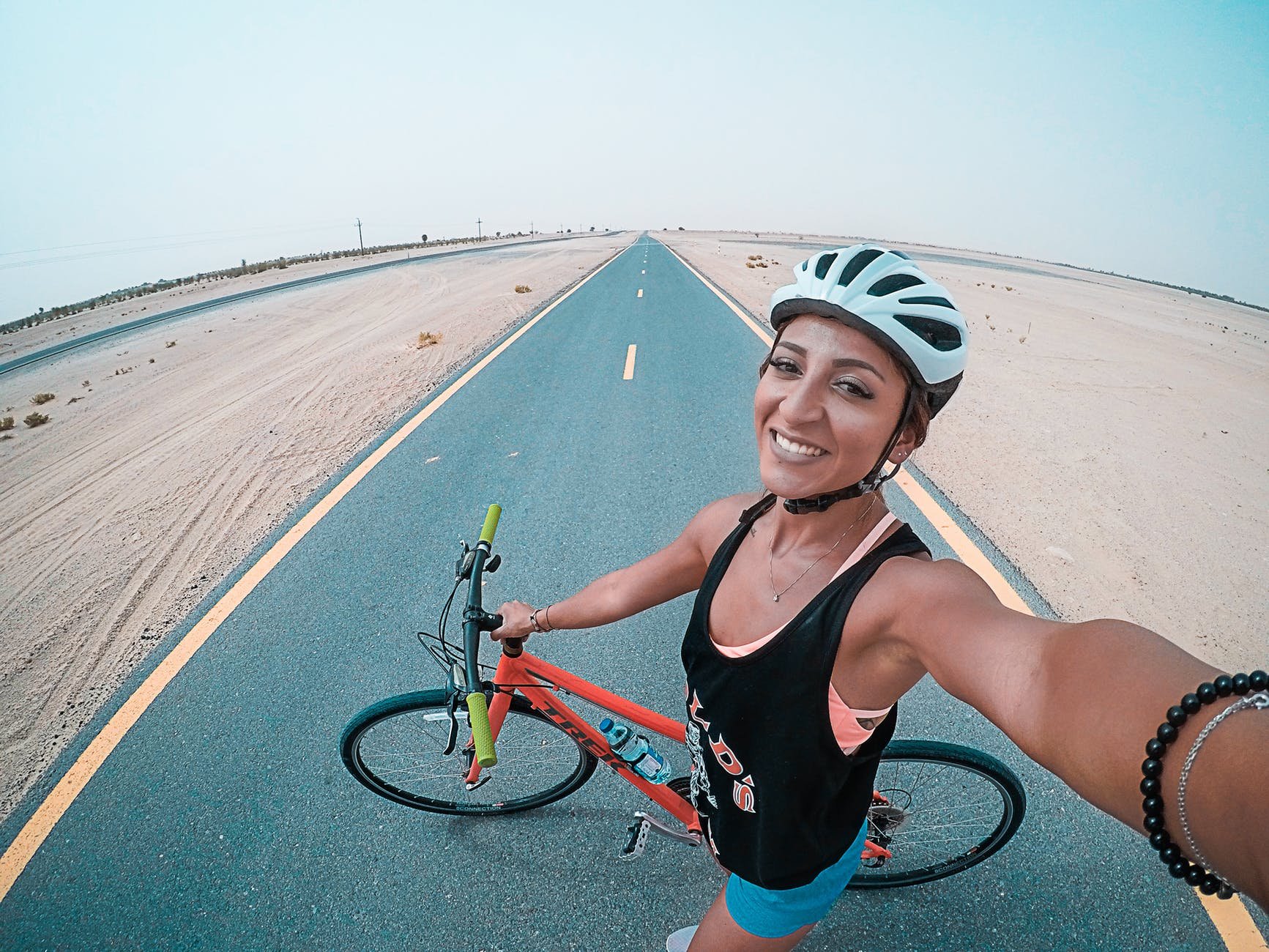 Mulher de capacete ao lado de bicicleta tirando selfie