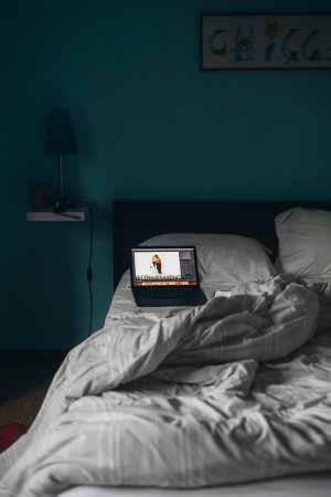 Computador em cima de uma cama no quarto escuro.