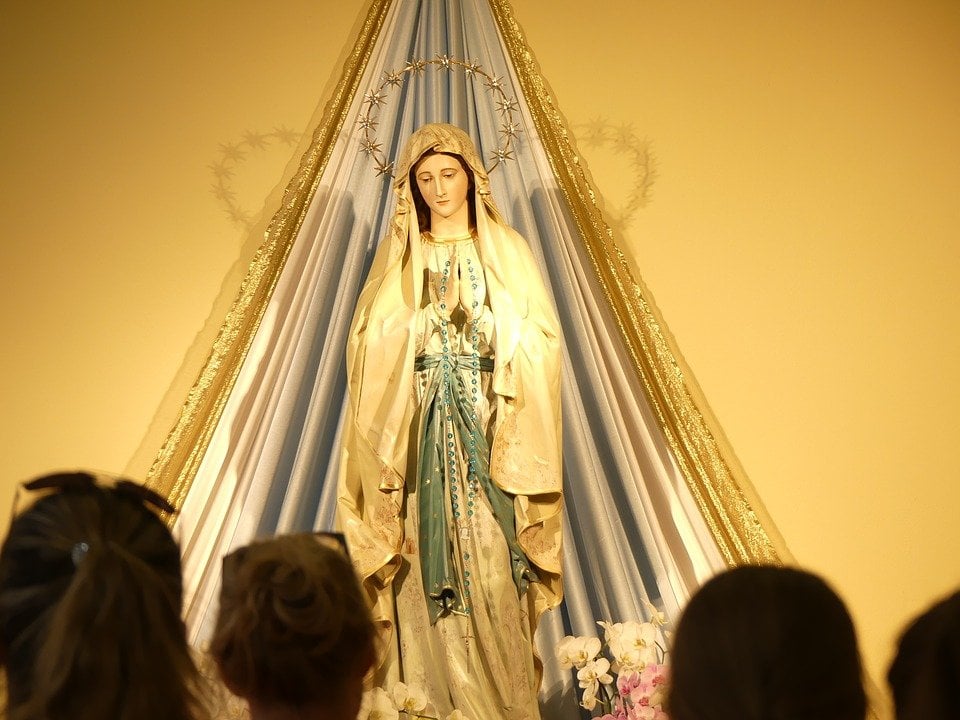 Estátua de Nossa Senhora em frente aos devotos.