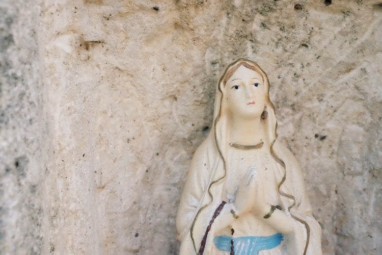 Estátua de Nossa Senhora rezando e olhando para cima.