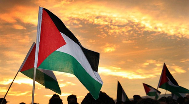 bandeira da Palestina sendo erguida ao pôr do sol.