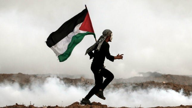 Manifestante corre segurando a bandeira da Palestina.