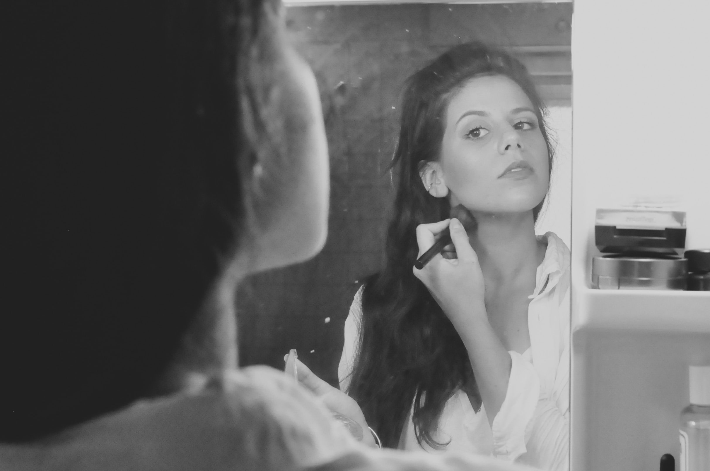 Mulher se maquiando em frente ao espelho.