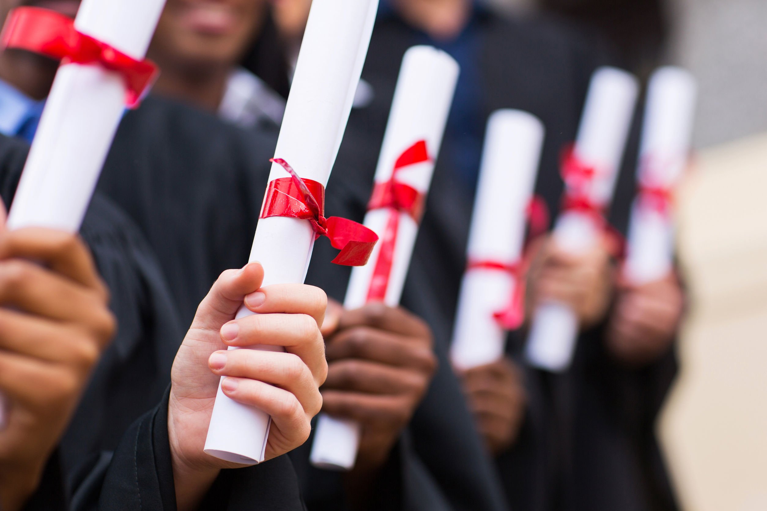 Imagem de pessoas segurando diplomas de formatura