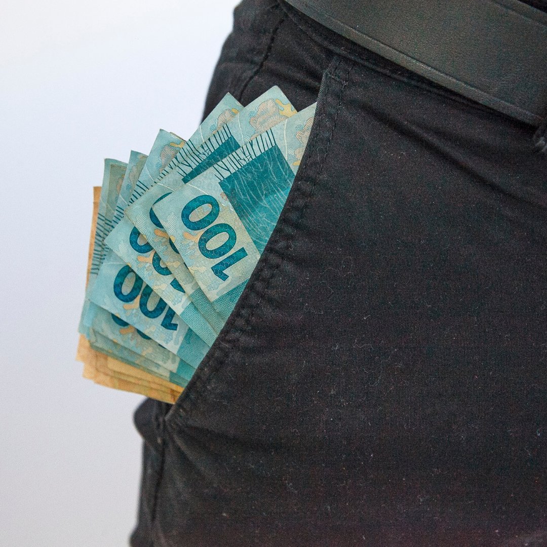 Diversas notas de dinheiro no bolso de uma calça