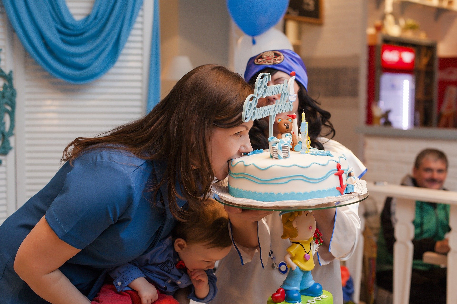 Mãe mordendo bolo em aniversário do filho.