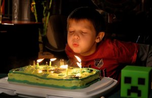 Menino assoprando velinhas de aniversário.