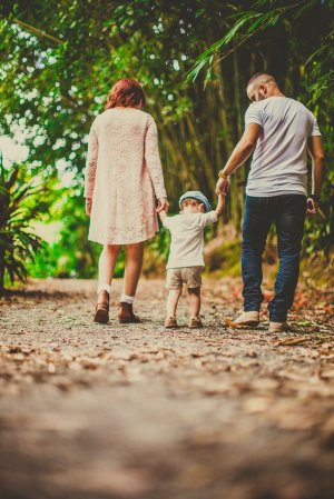 Pais caminhando com filho pequeno em um parque.