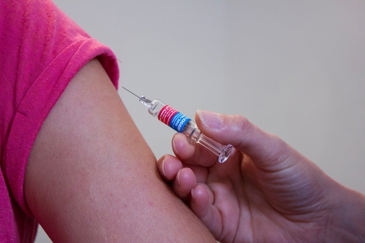 Braço de criança recebendo injeção de vacina.
