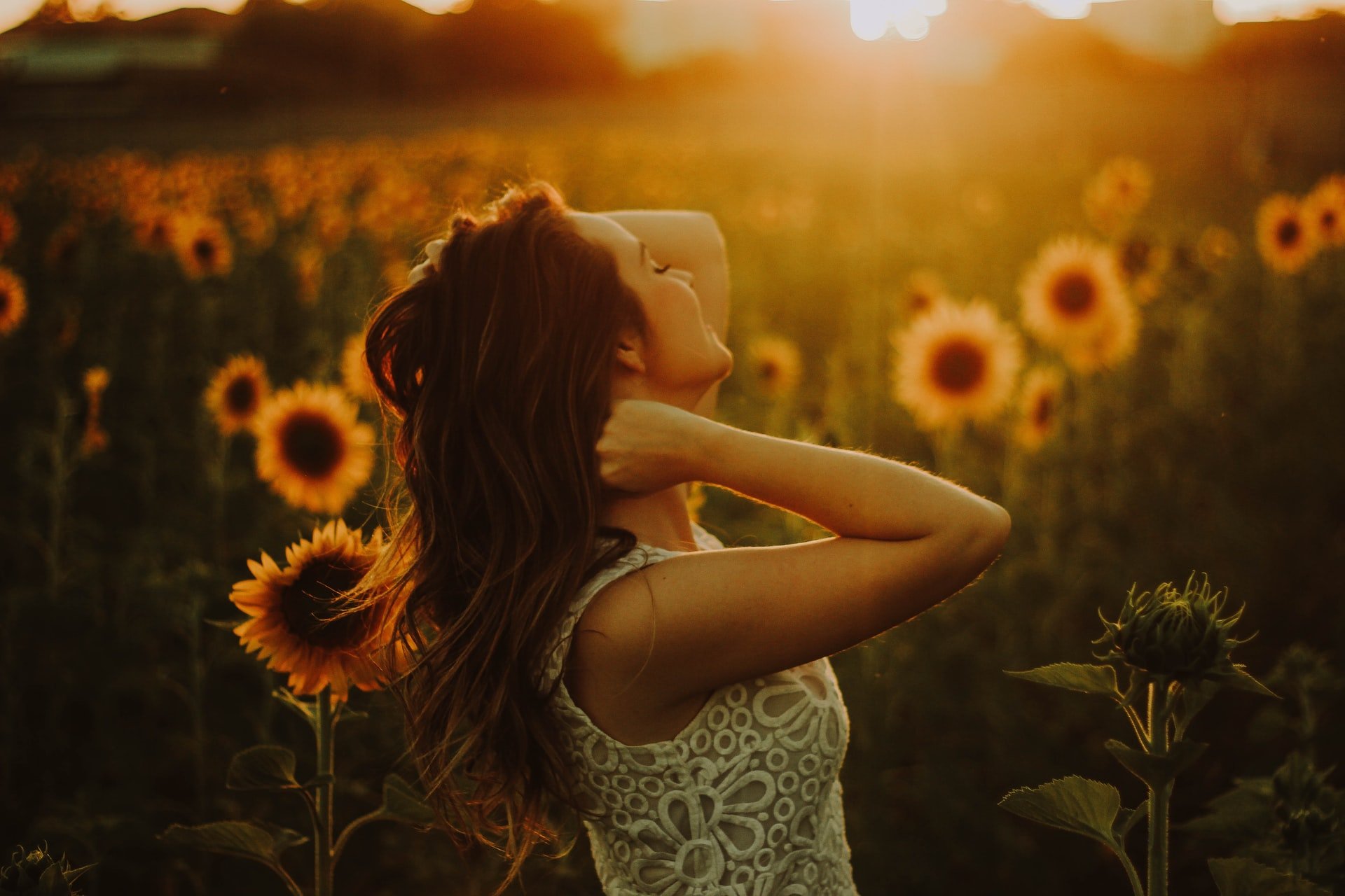 Rodolfo Sanches Carvalho / Unsplash Mulher branca num campo de girassóis.