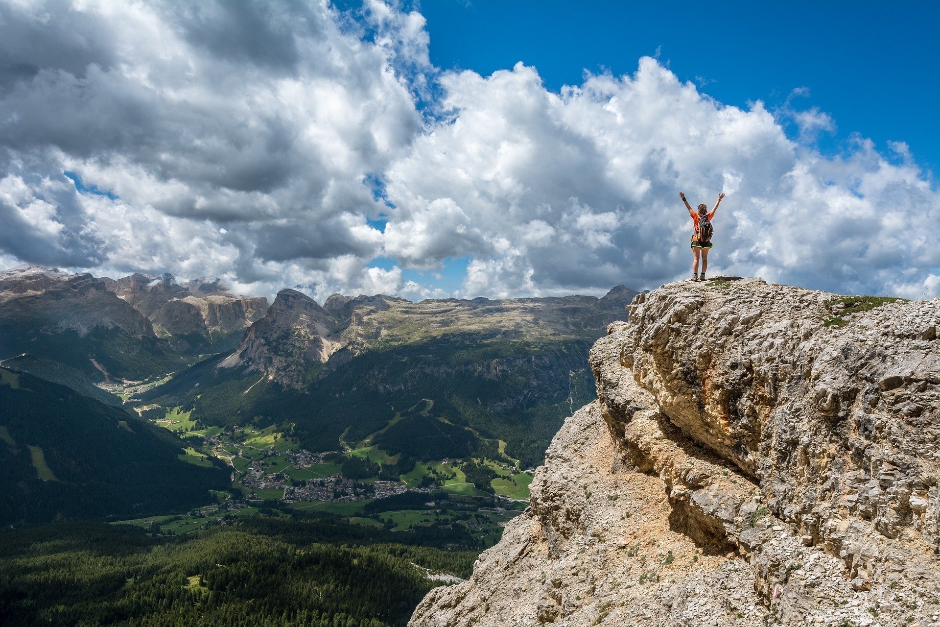 Foto de pessoa de braços abertos no alto de uma montanha