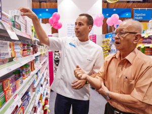 Farmacêutico mostrando medicamentos em prateleira para senhor idoso.