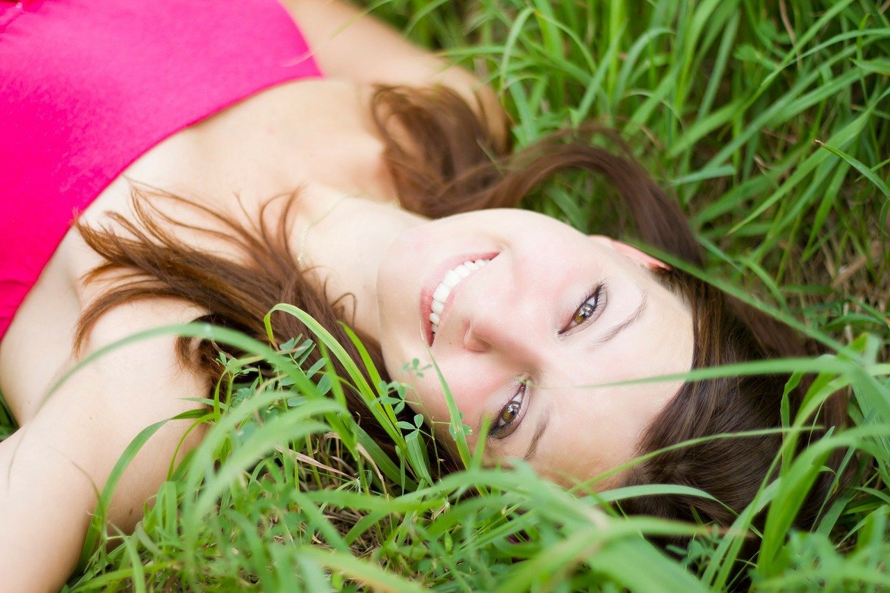 Mulher deitada no gramado sorrindo