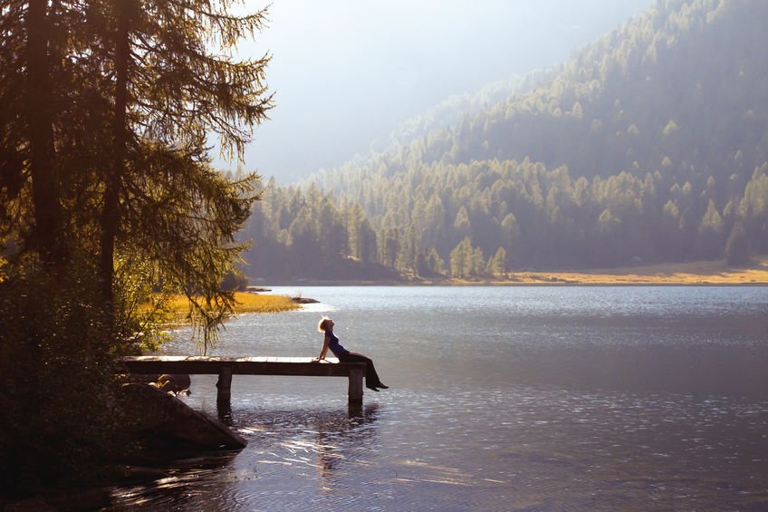 Pessoa sentada na beira de lago.