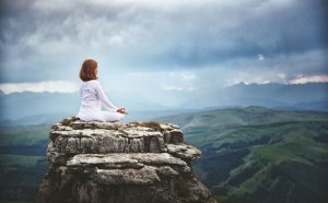 Mulher meditando em penhasco.