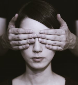 Homem cobrindo o rosto de mulher com as mãos