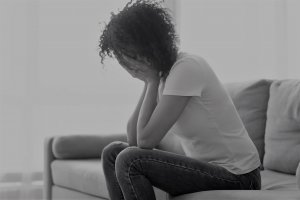 Mulher sentada na sala com as mãos no rosto