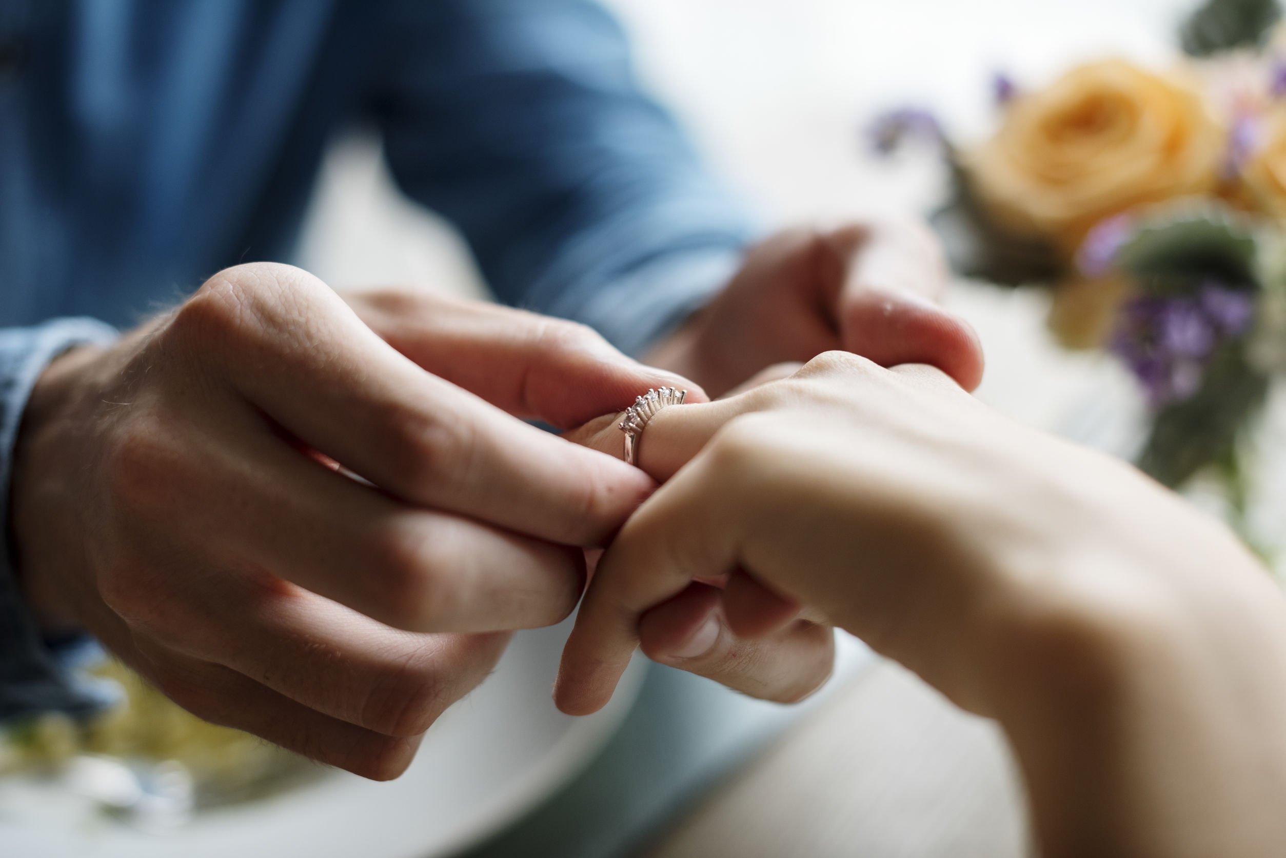 Foto de noivo colocando aliança de casamento na mão da noiva