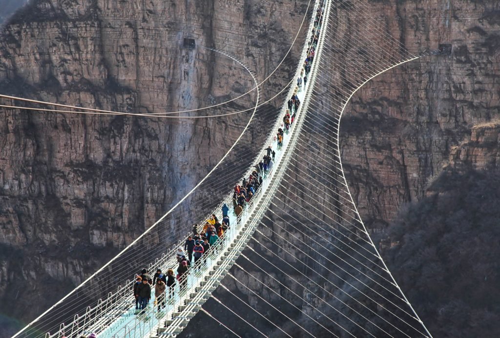 Imagem da ponte de vidro com pessoas caminhando