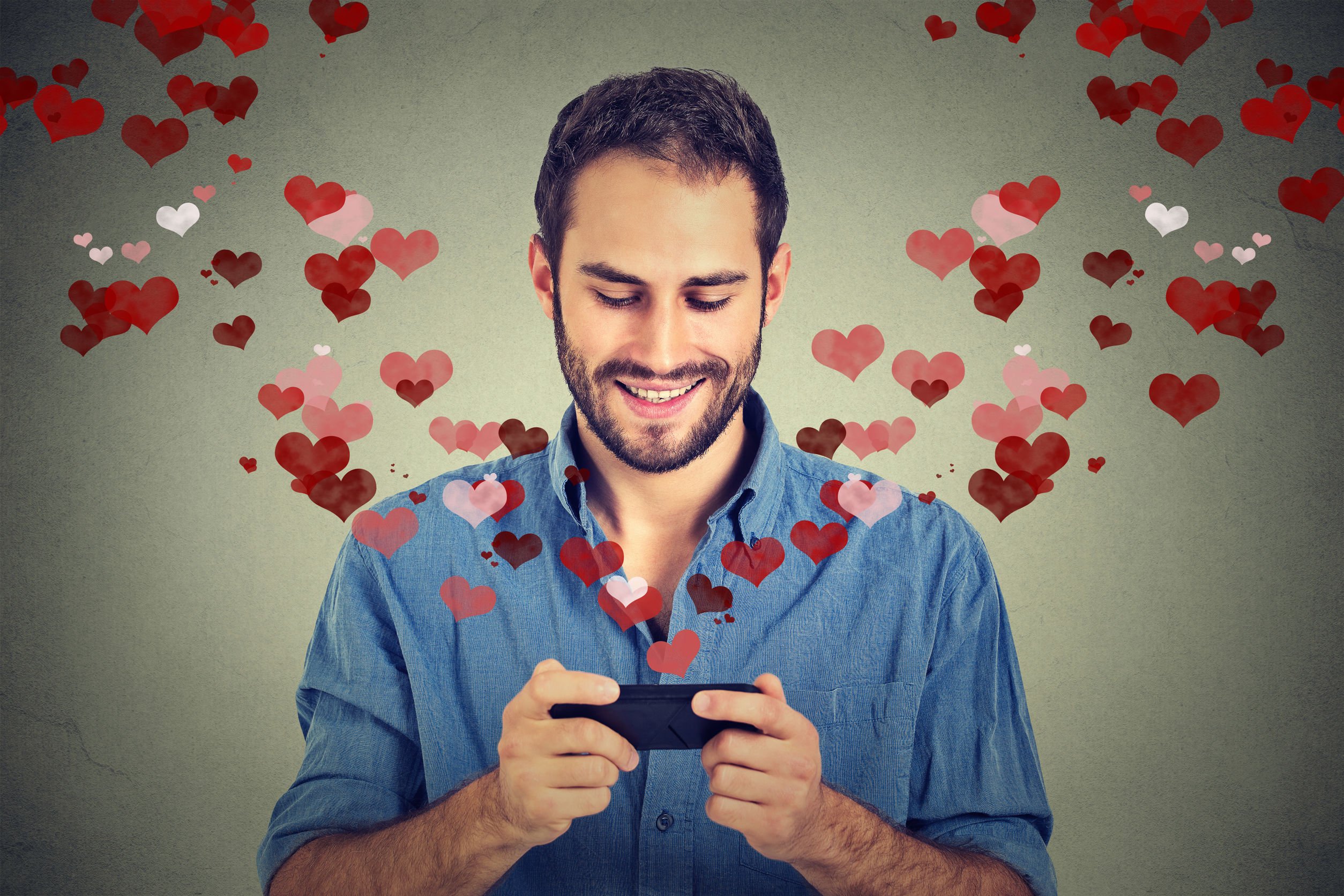 Imagem de homem vendo celular, e corações saindo da tela