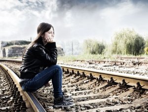 Mulher sentada nos trilhos do trem.