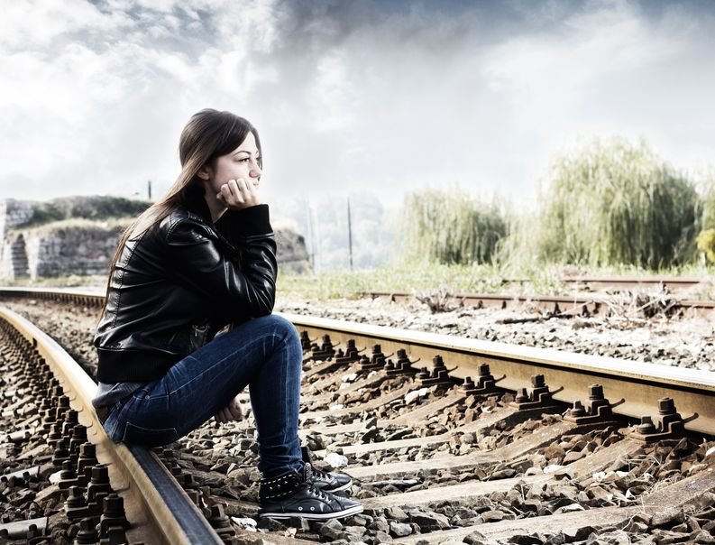 Mulher sentada nos trilhos do trem.