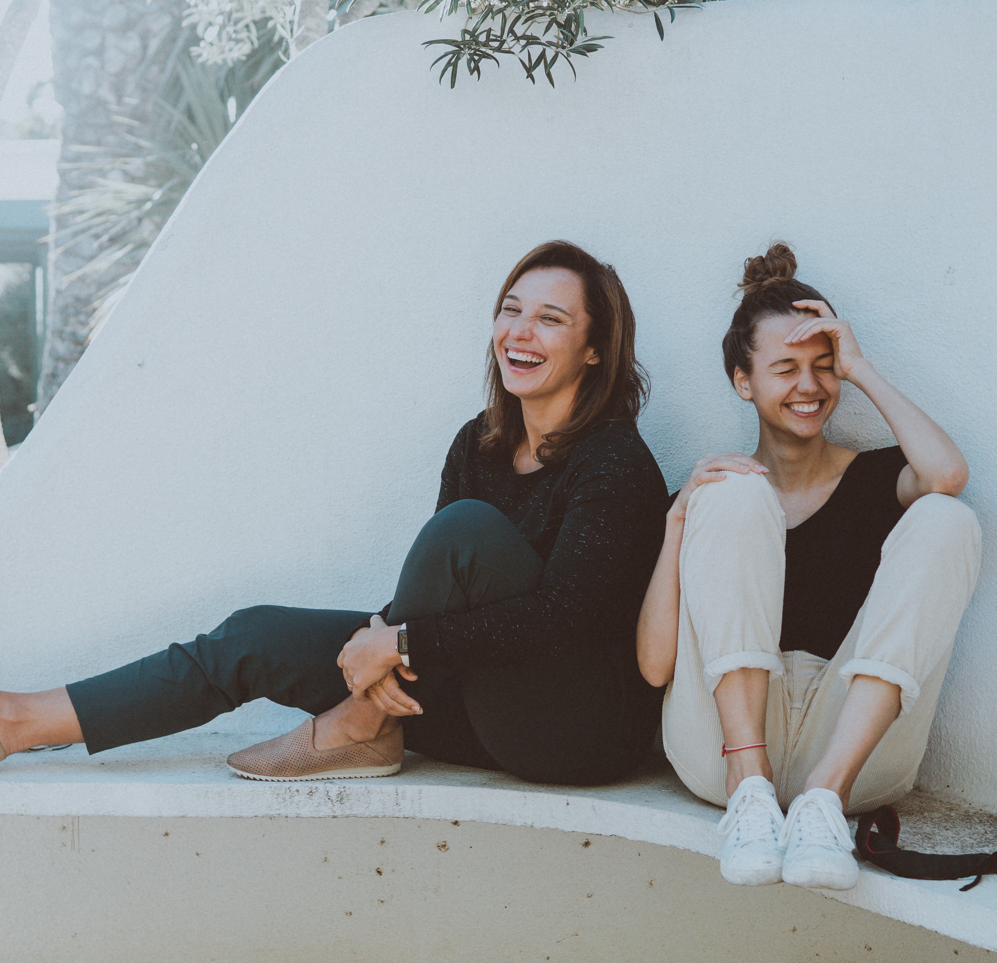 Duas mulheres rindo sentadas no banco de praça
