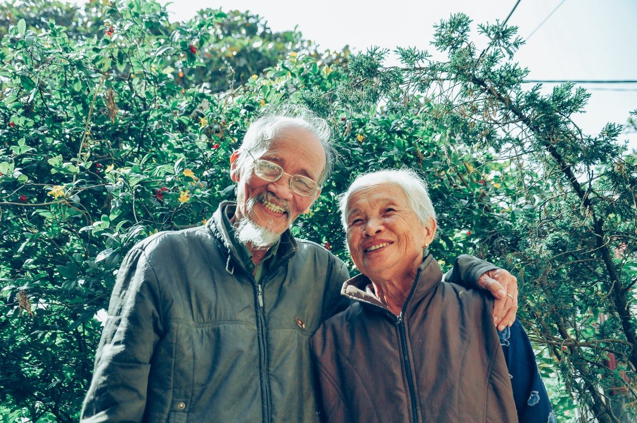 Casal de idosos sorrindo abraçados.