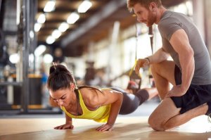 Mulher fazendo flexões e personal trainer