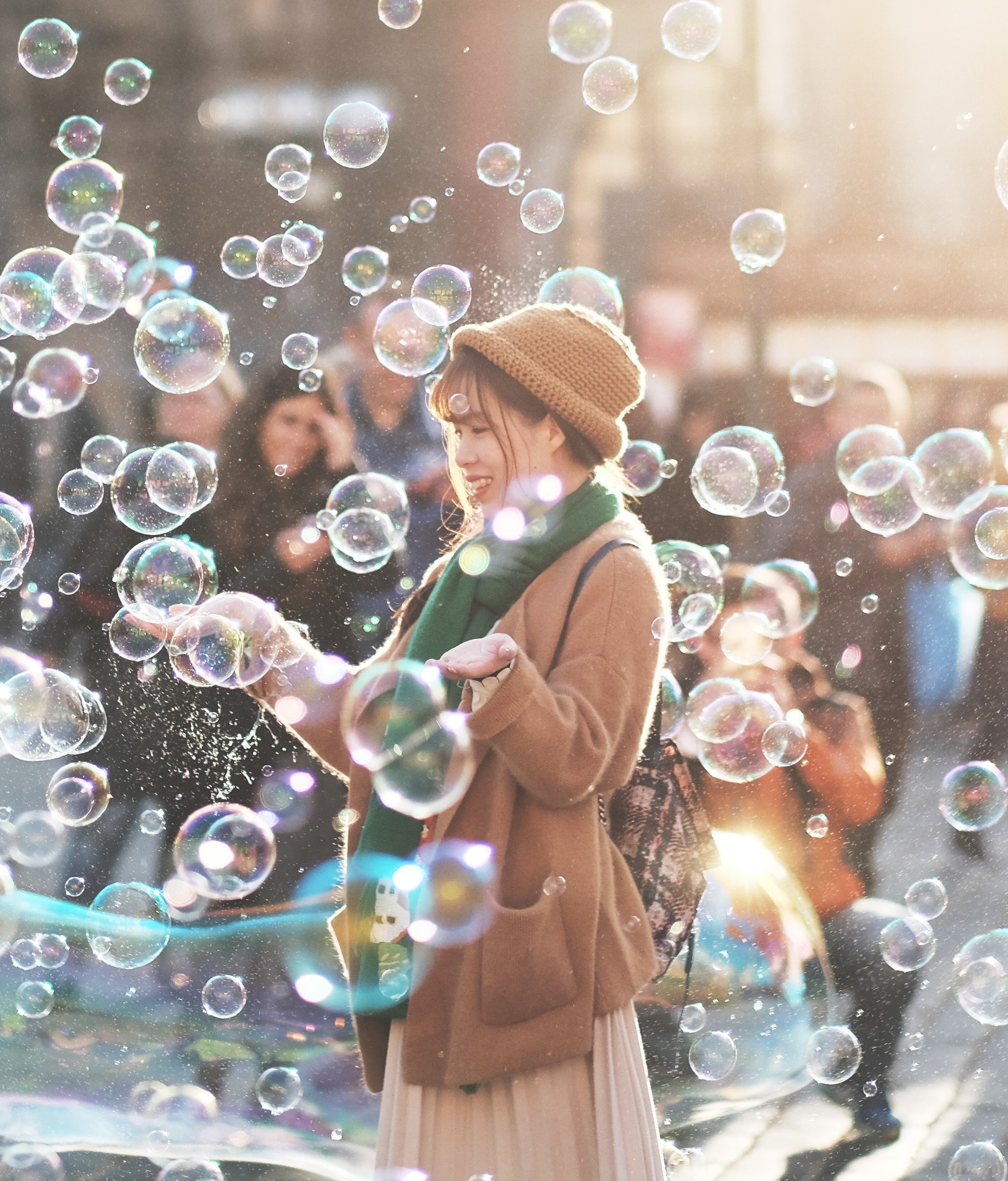 Mulher no meio da rua com bolhas de sabão e pessoas ao seu redor