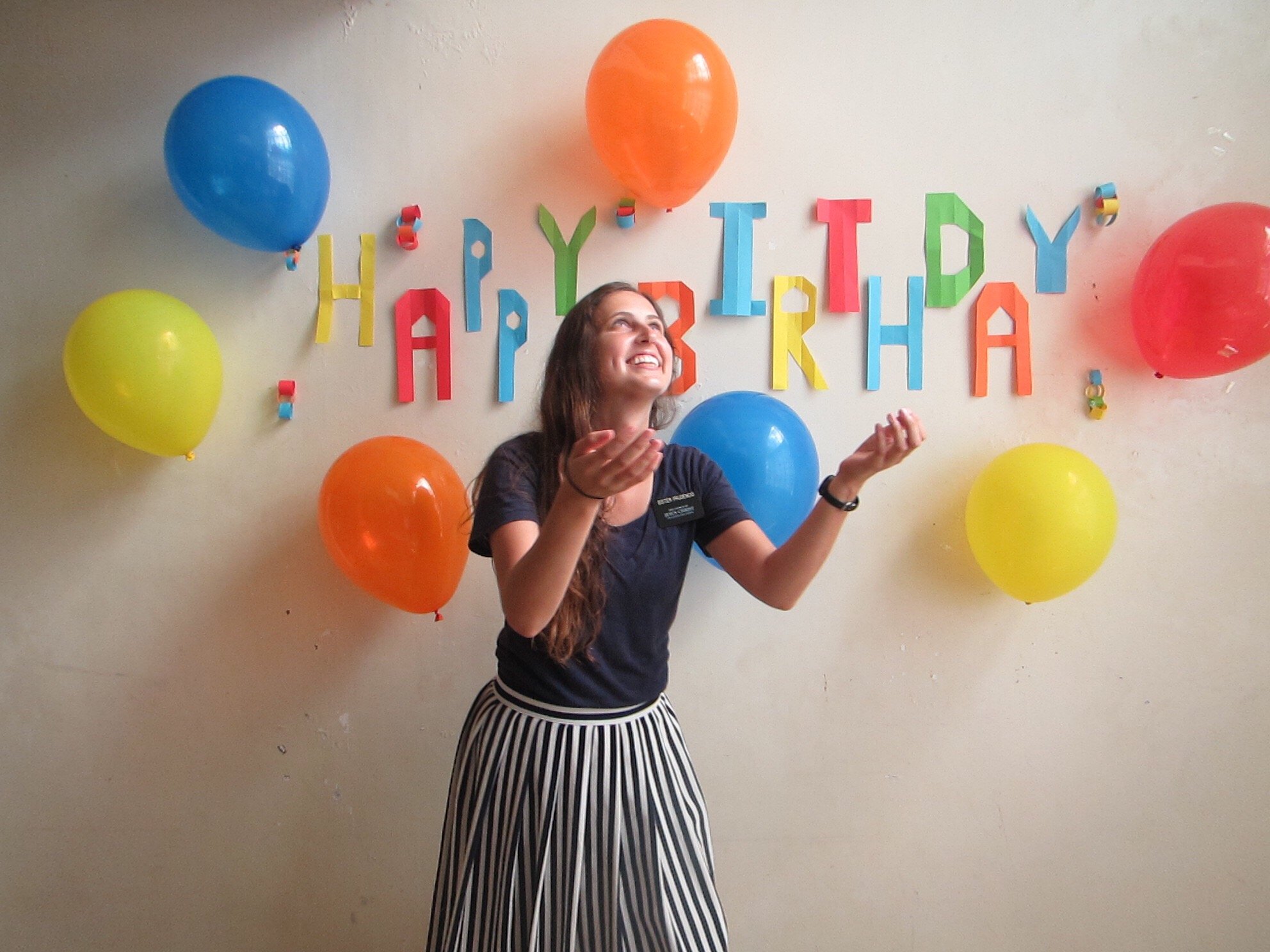 Mulher de frente para decoração de aniversário com balões, olhando para cima