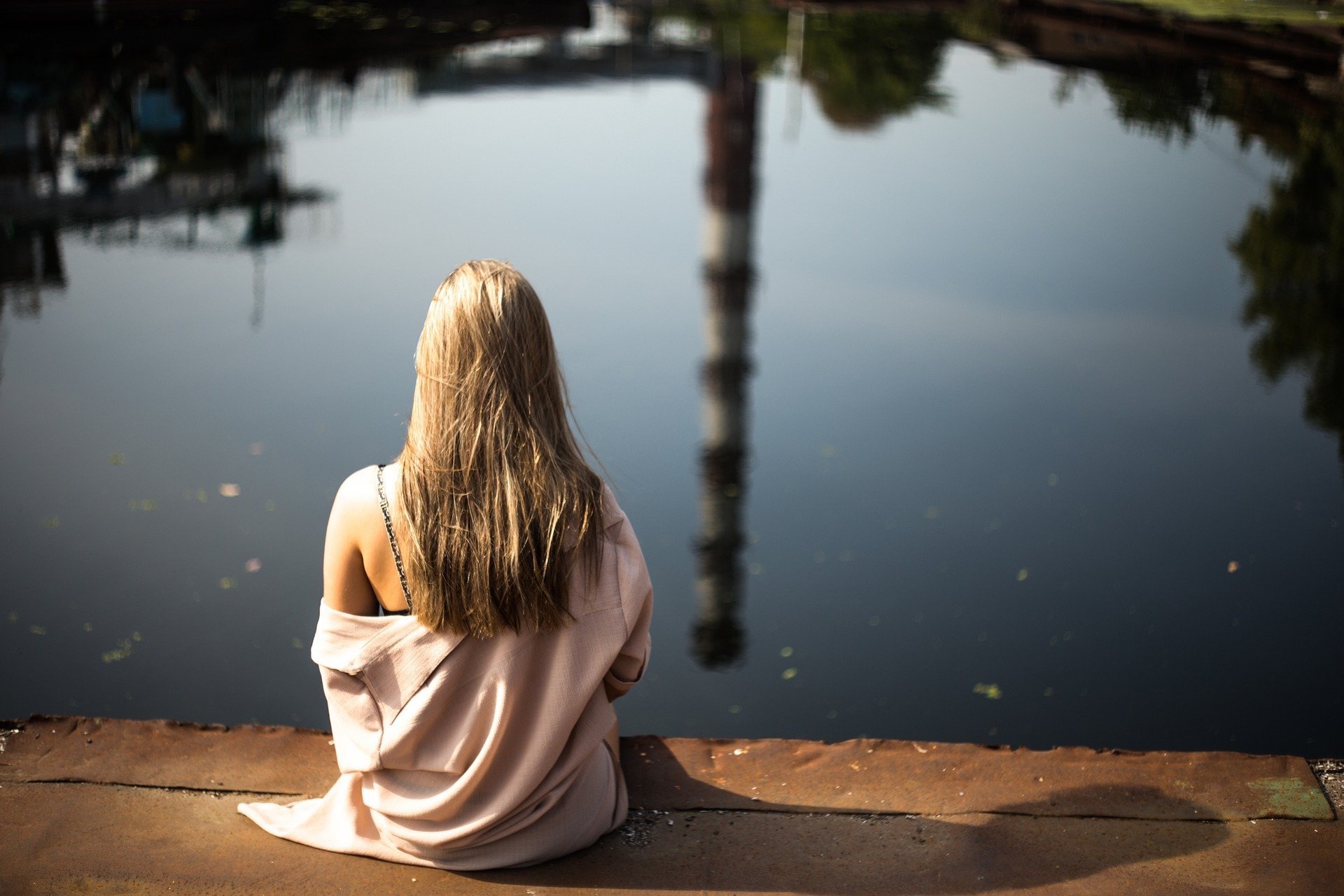 Foto de mulher sentada olhando lago