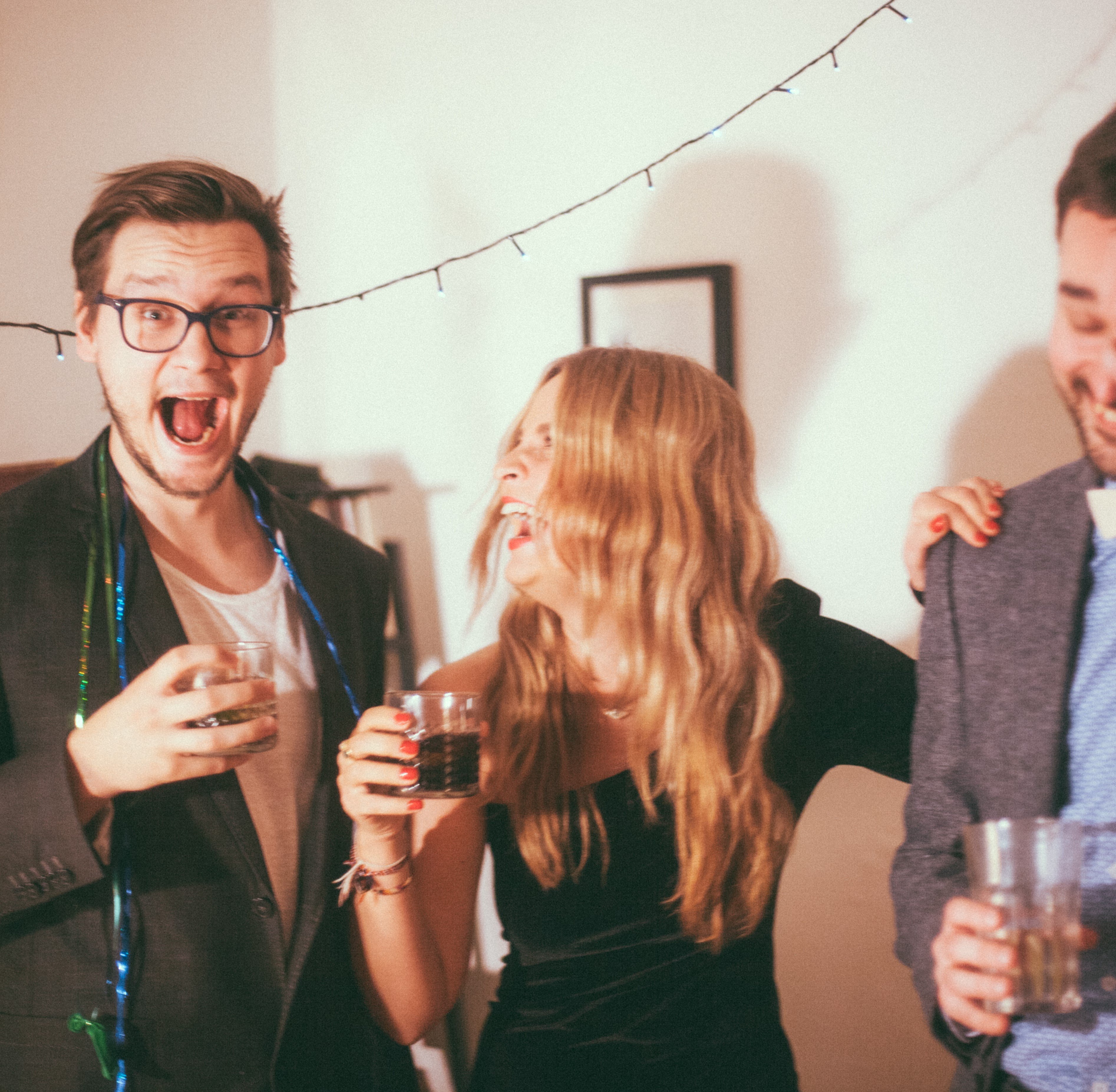 Três pessoas rindo e segurando copo de bebida na mão