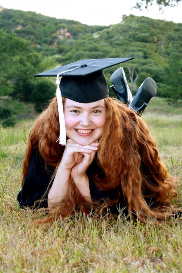 Foto de menina deitada na grama usando roupa de formatura