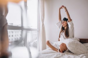 Mulher se espreguiçando na cama.