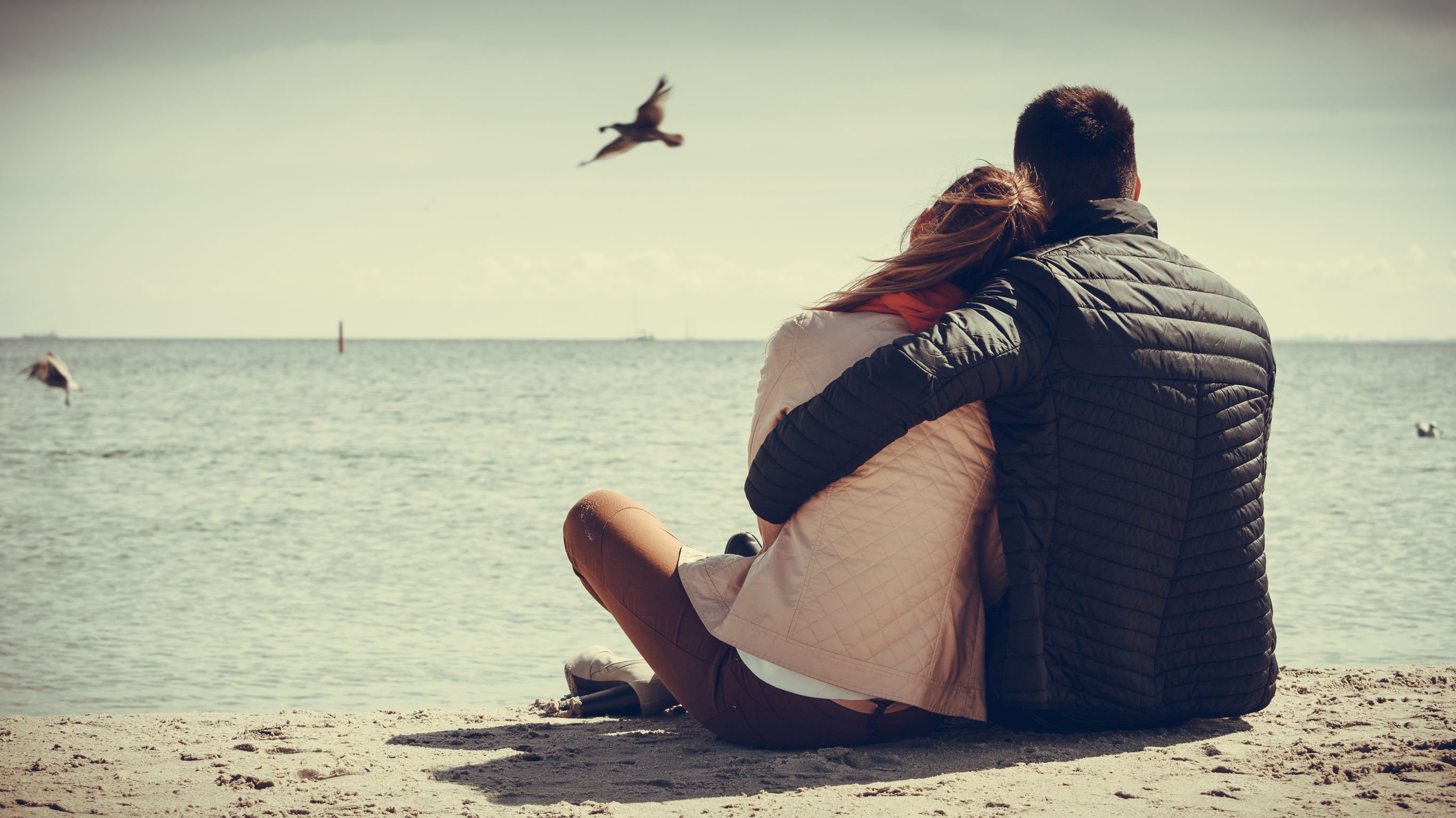 Foto de casal abraçado vendo o mar