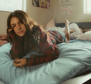 Mulher deitada na cama, apoiando a mão no rosto