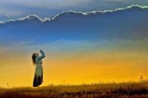 Menina de mãos juntas erguidas aos céus