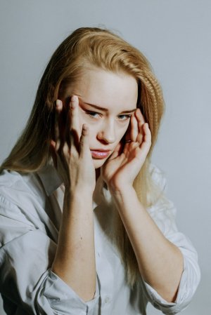 Mulher estressada com as mãos segurando o rosto.