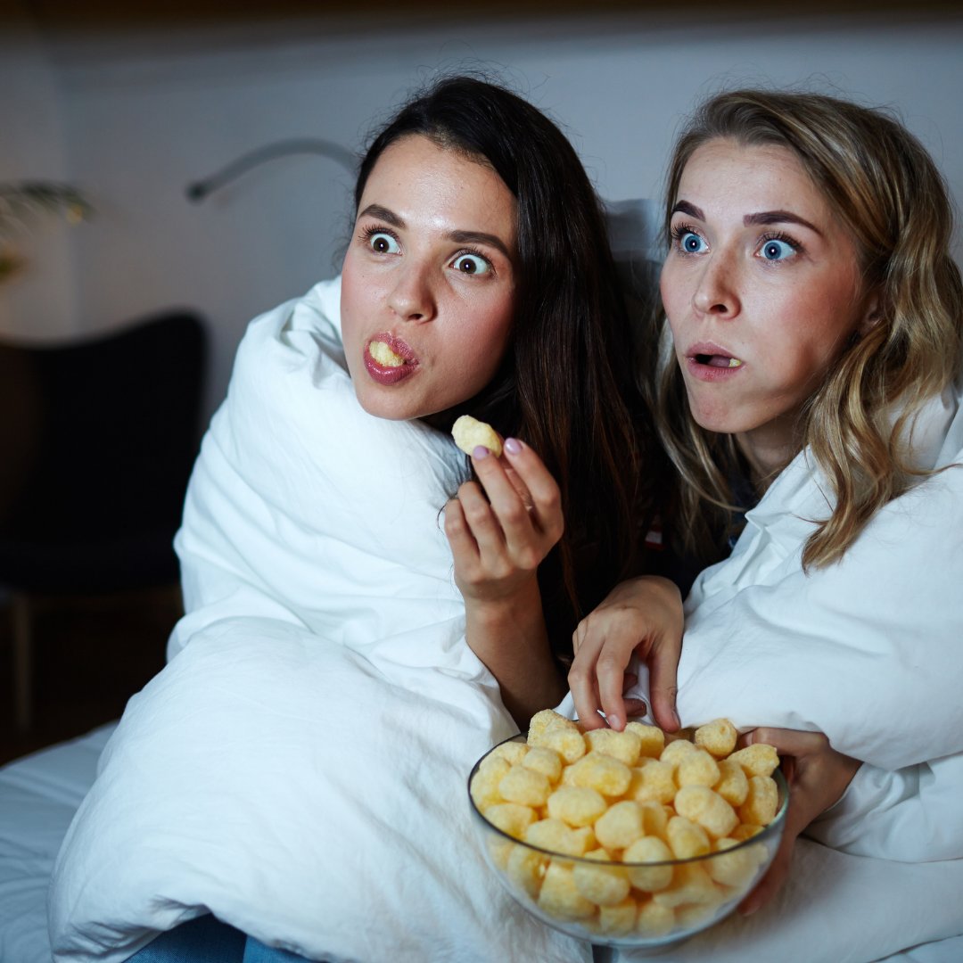 Meninas enroladas em cobertor comendo salgadinhos