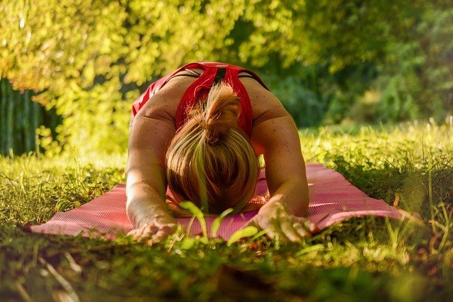 Mulher fazendo yoga em grama