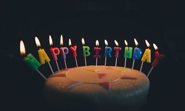 Bolo de aniversário com velas formando 'Happy Birthday'
