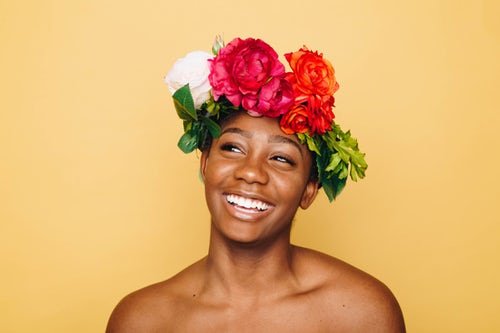 Mulher negra com coroa de flores na cabeça, sorrindo