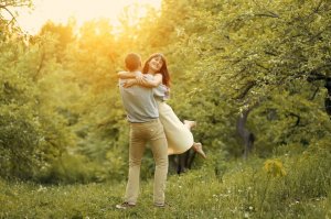 Casal sorrindo na floresta.