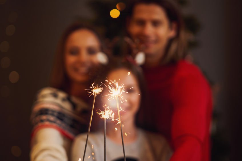 Mãe, pai e filha segurando vela de estrelinha.